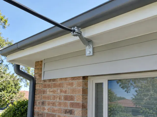 Overhead service cable and wall-mounted point-of-attachment bracket on a brick and weatherboard house in Fullerton Cove